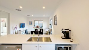 Une cuisine moderne équipée d’un évier en acier inoxydable, d’une machine à café et d’un four à micro-ondes.