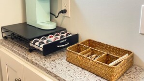 A coffee maker on a countertop, a drawer with coffee pods, and a woven basket.