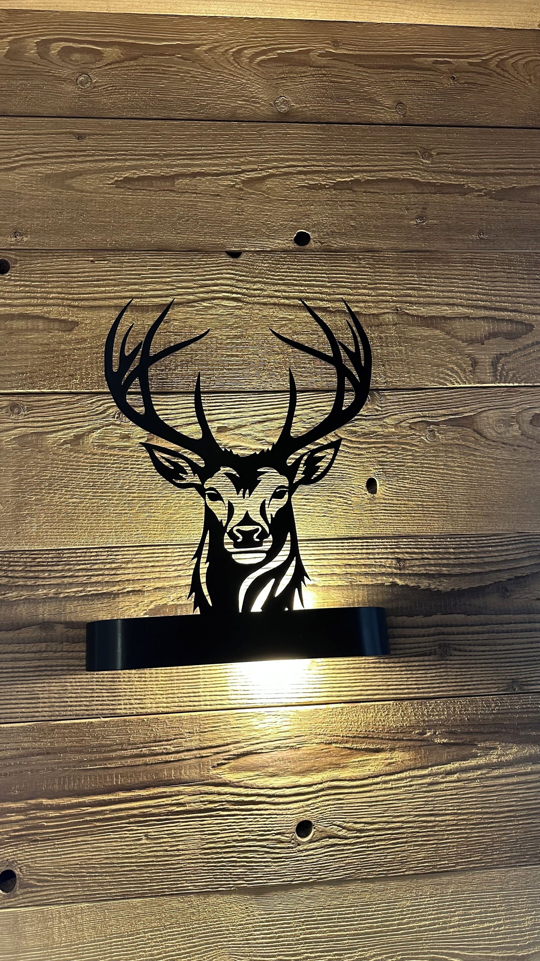 Una superficie in legno con una testa di cervo intagliata al centro.