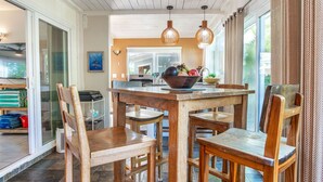 A wooden dining table with four chairs, a bowl of fruit, and pendant lights. - Sunrise Tropical Garden Getaway (Pahoa)