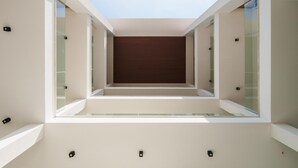A modern interior with a central dark wooden panel, glass walls, and recessed lighting. - Welcomely - Light Room Vistamare - Sergio Endrigo (Olbia)