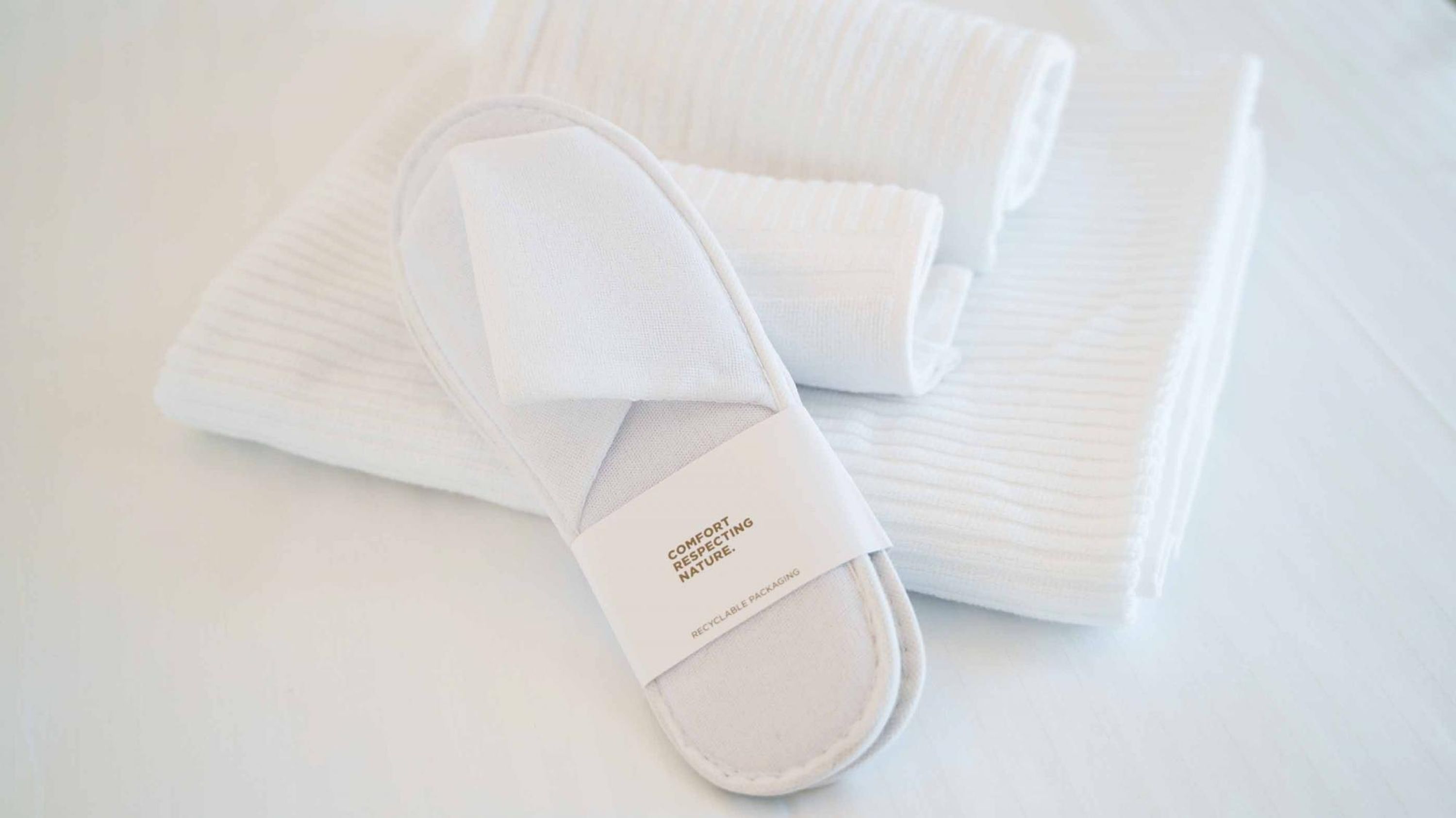 Un par de zapatillas blancas con una etiqueta que dice 'Comfort Respetando la Naturaleza' y 'Embalaje Reciclable'.