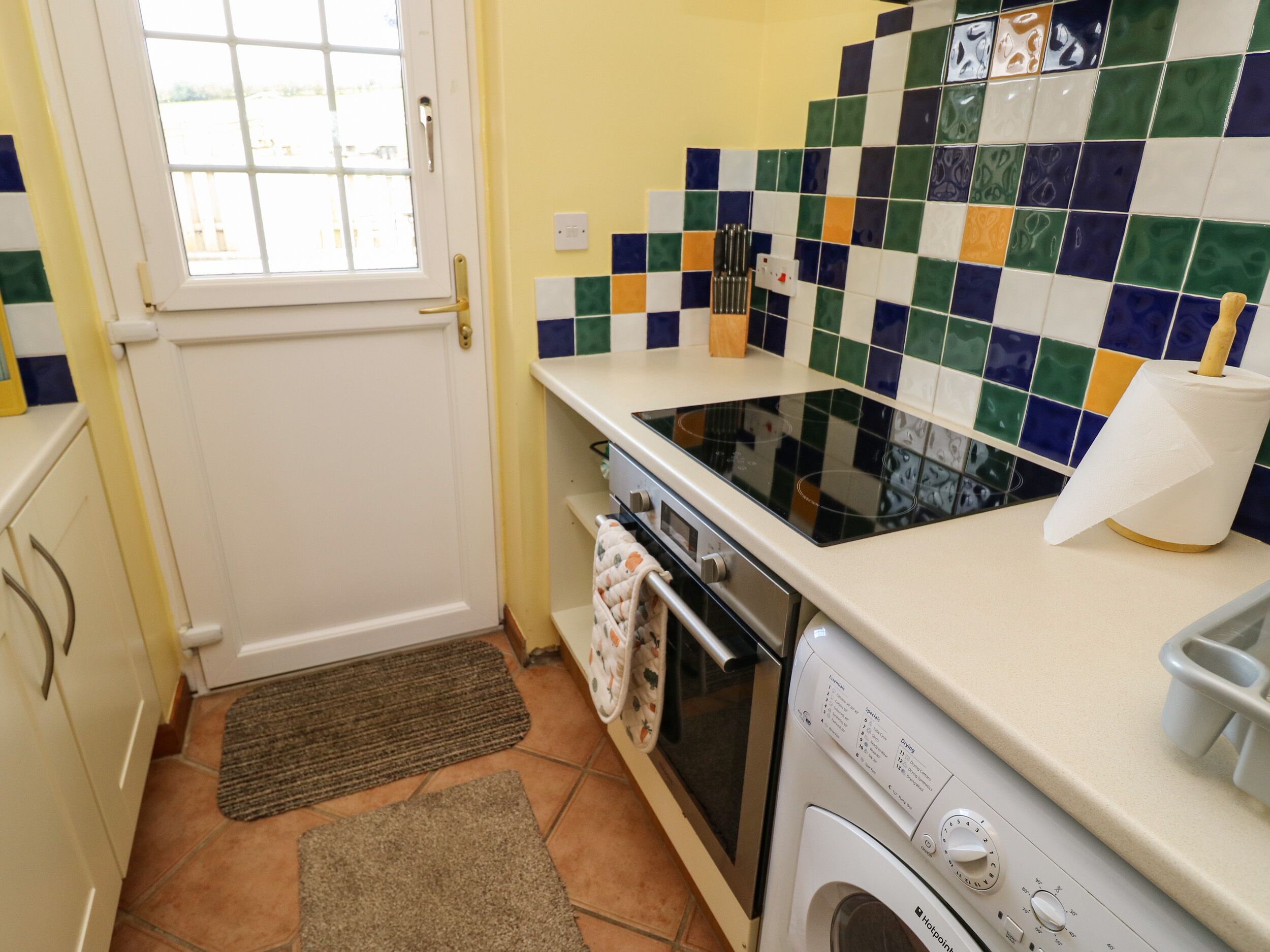 Une cuisine compacte équipée d’une cuisinière, d’un four et d’un lave-linge.