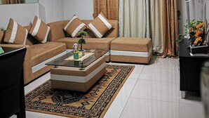 A living room with a sectional sofa, a coffee table, a rug, and a ceiling light fixture. - 150 Newport condotel pasay  (Pasay)