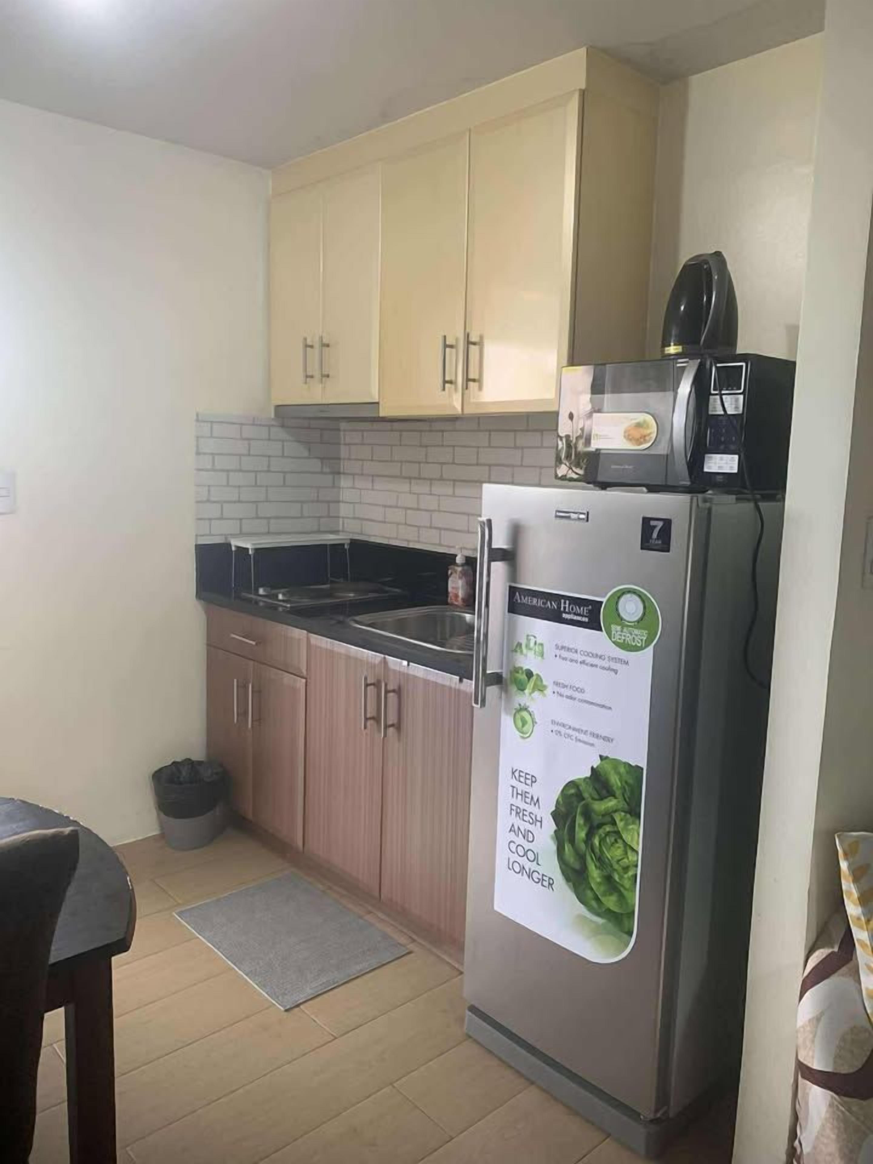 A compact kitchen with a refrigerator, a microwave, and a sink.