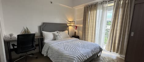 Un dormitorio ordenado con una cama, un escritorio y una silla.
