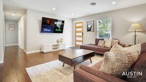 Un salon moderne avec un téléviseur à écran plat fixé au mur, un canapé en cuir marron, une table basse en bois et une console blanche.