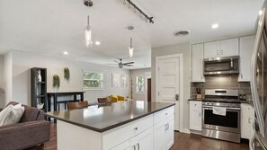 A modern kitchen with white cabinets, stainless steel appliances, and a central island.