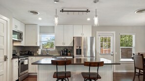 A modern kitchen with white cabinets, stainless steel appliances, and a central island with bar stools. - Eastcrest Dr xxxxxxx (Austin)
