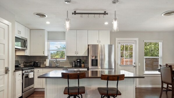 A modern kitchen with white cabinets, stainless steel appliances, and a central island with bar stools.