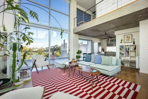 Un salon moderne avec une grande fenêtre, un canapé, une table basse et un tapis rayé rouge et blanc.