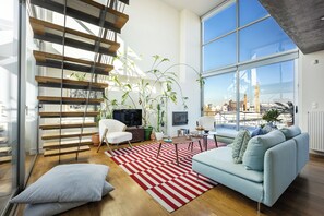 A modern living room with a sofa, a coffee table, a TV, and a staircase.