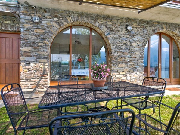 An outdoor patio with a stone wall, a metal table, and chairs.