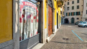 Un edificio con fachada amarilla y un escaparate que muestra un letrero que dice 'PANIFICIO PASTICCERIA SACCHETTO'.