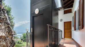 Un edificio moderno con un muro de piedra, una puerta de madera y vistas a un lago y montañas.