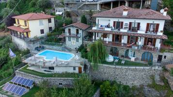 Une villa dotée d’une piscine, de murs en pierre et d’un balcon donnant sur la piscine.