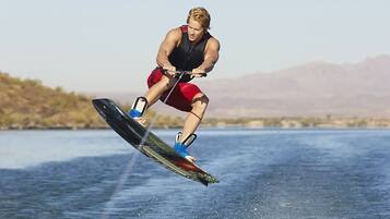 A person wakeboarding on a body of water with mountains in the background.