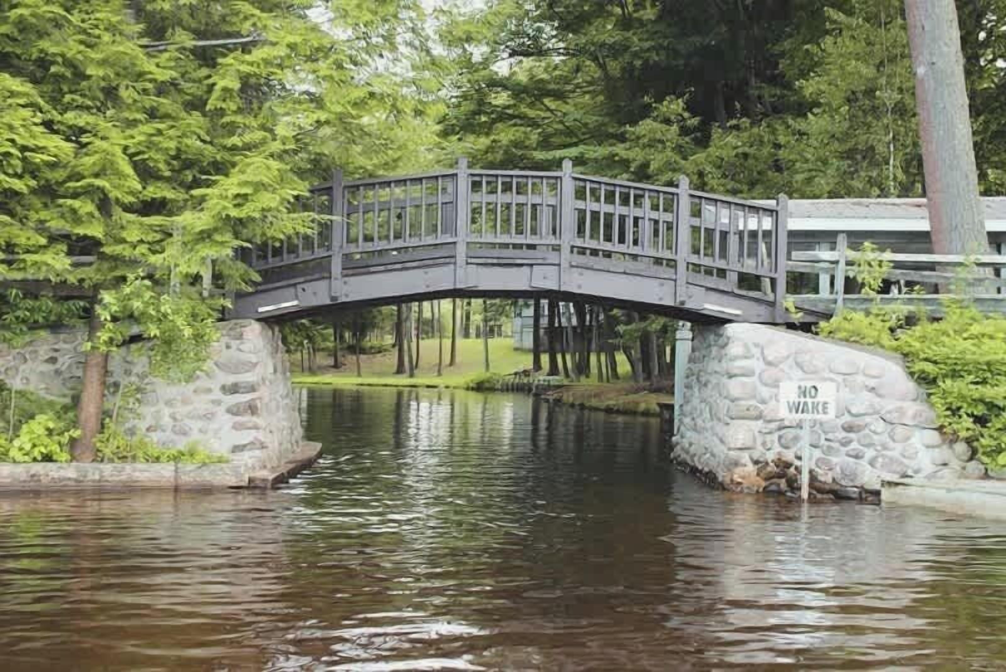 Un puente de piedra sobre un río tranquilo, rodeado de abundante vegetación.