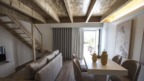 A modern living room with a sofa, dining table, chairs, and a staircase. - Casa das Amendoeiras (Briteiros (Santo Estêvão))