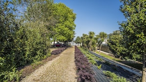A paved pathway flanked by lush greenery and a water feature. - Casa das Amendoeiras (Briteiros (Santo Estêvão))