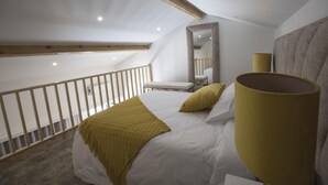 A bedroom with a bed, a large mirror, a bench, and a yellow lamp. - Casa das Amendoeiras (Briteiros (Santo Estêvão))