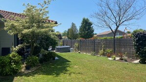 Un jardin avec une pelouse, une clôture en bois et un arbre.