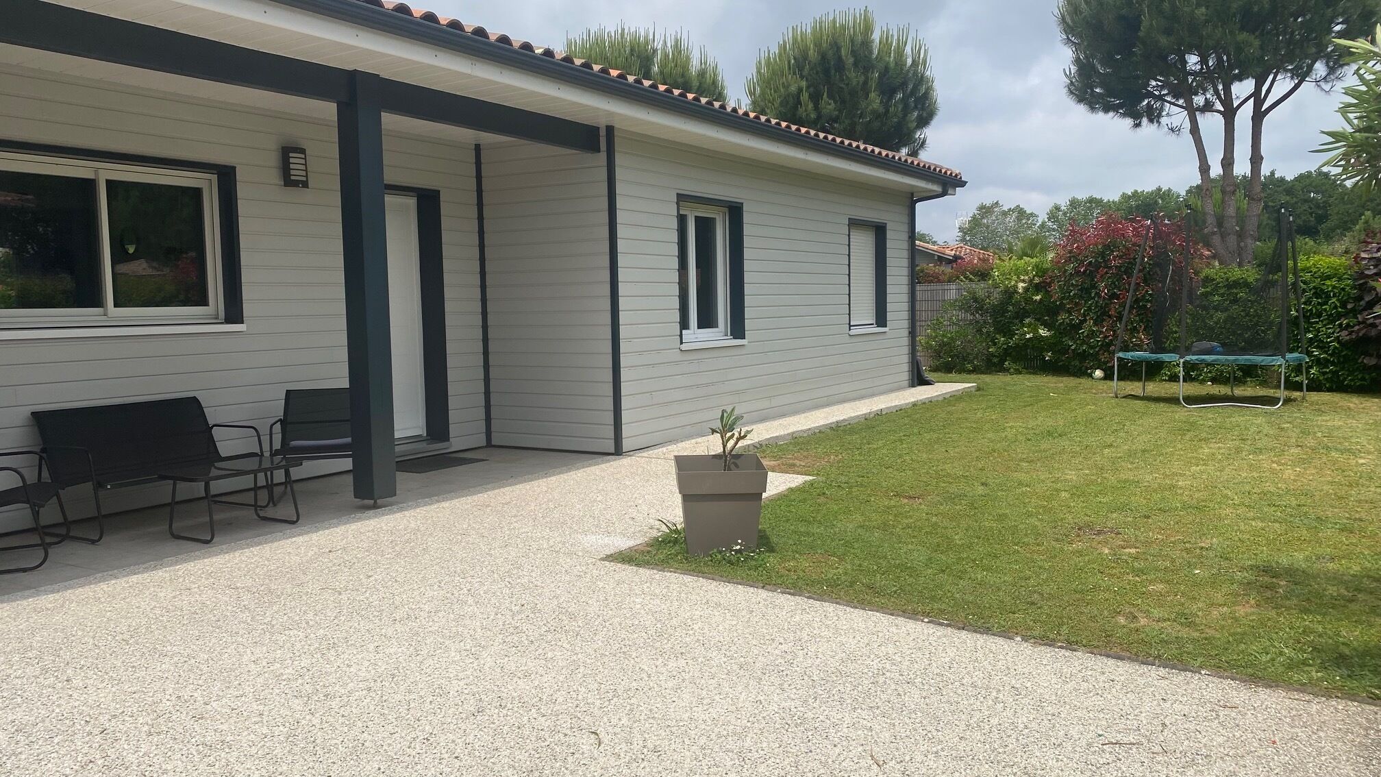 Une maison de plain-pied dotée d’un patio couvert, d’une petite pelouse et d’un trampoline.