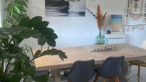 Un coin repas avec une table en bois, deux chaises, un luminaire suspendu et des œuvres d’art murales.