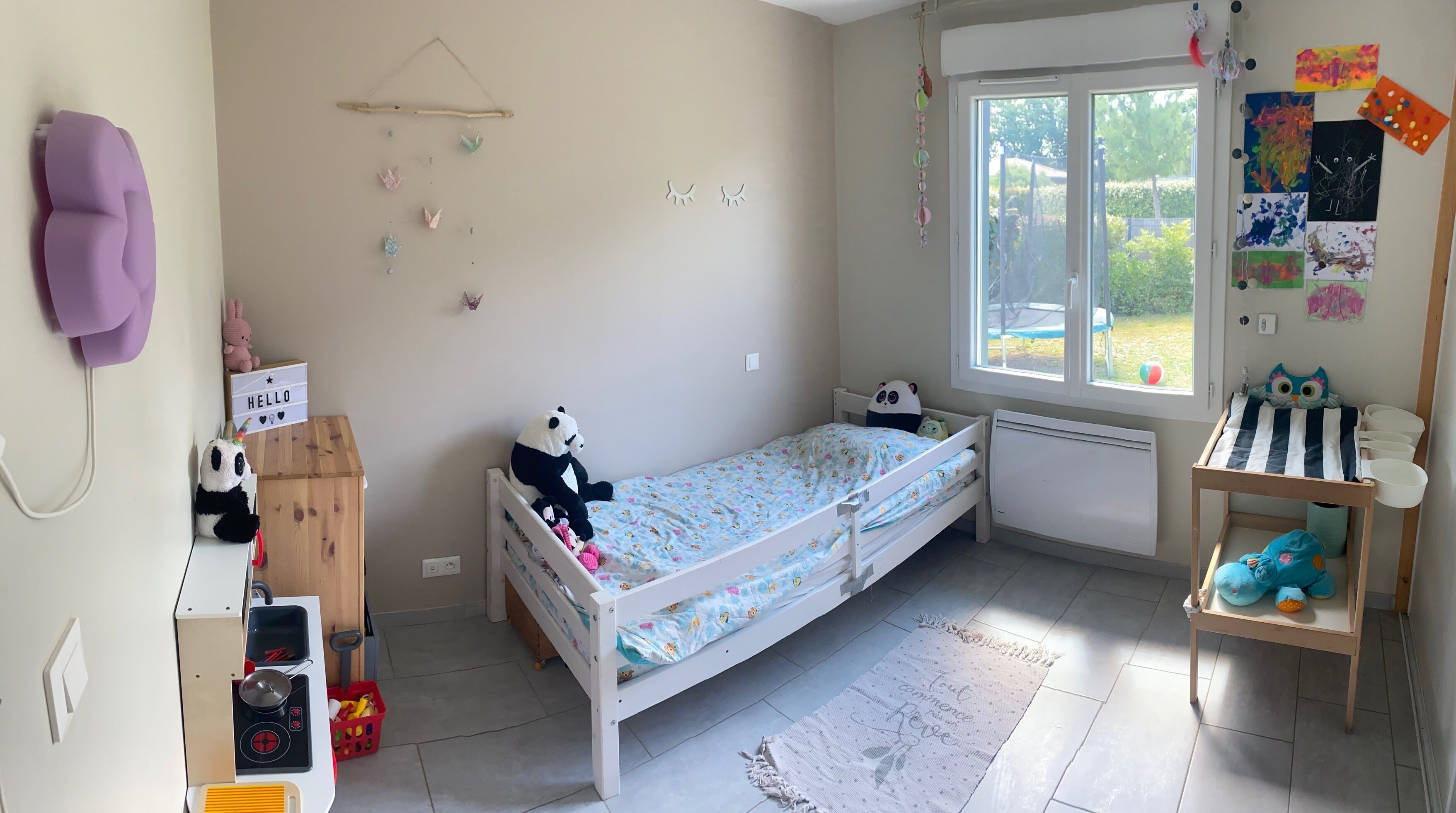 A child's bedroom with a bunk bed, a small desk, and a window with a view of the outdoors.
