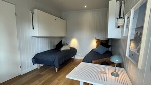 Ein kleines Zimmer mit zwei Betten, einem weißen Tisch und einer Pendelleuchte.