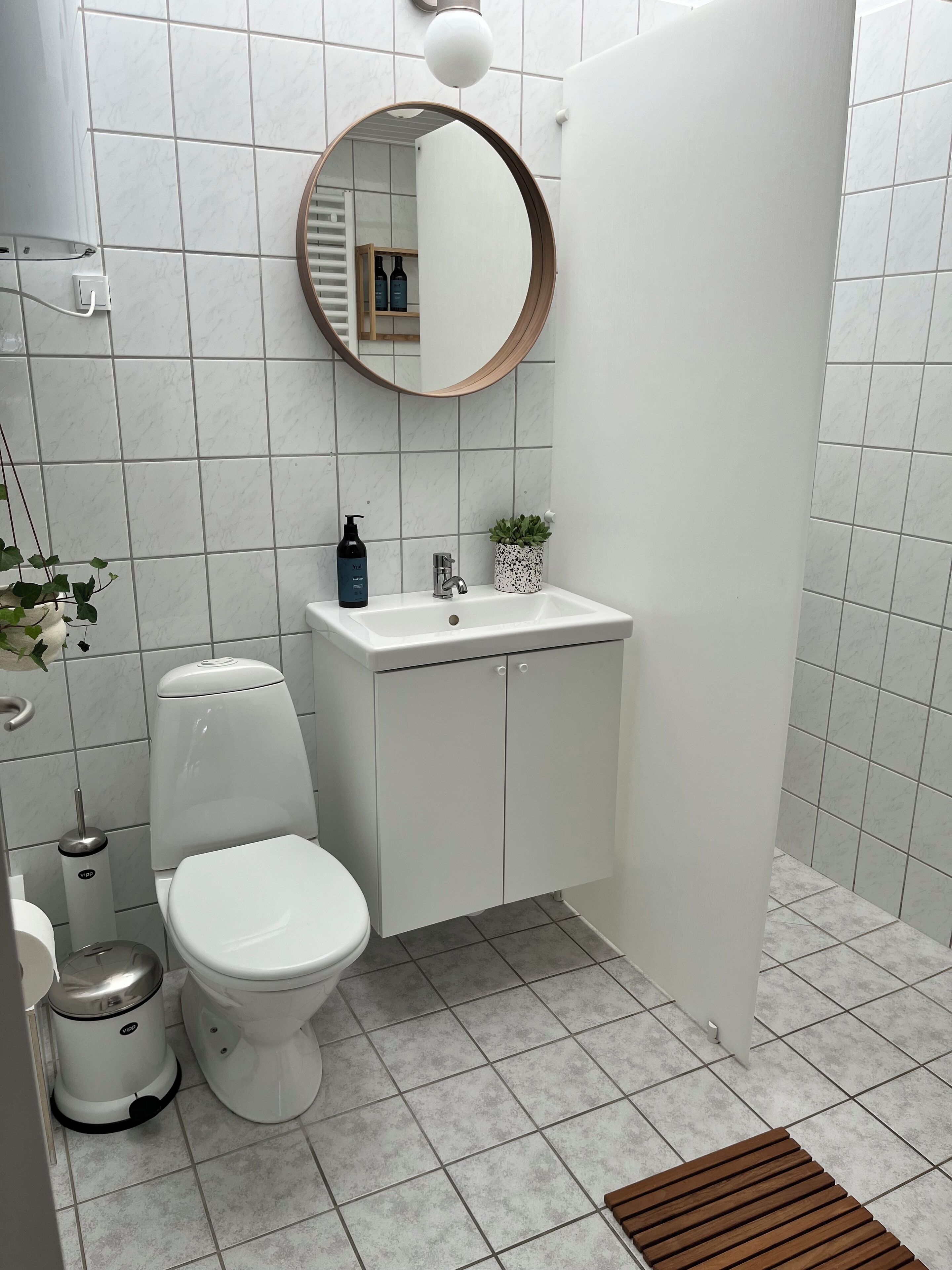 A modern bathroom with a toilet, sink, and mirror.