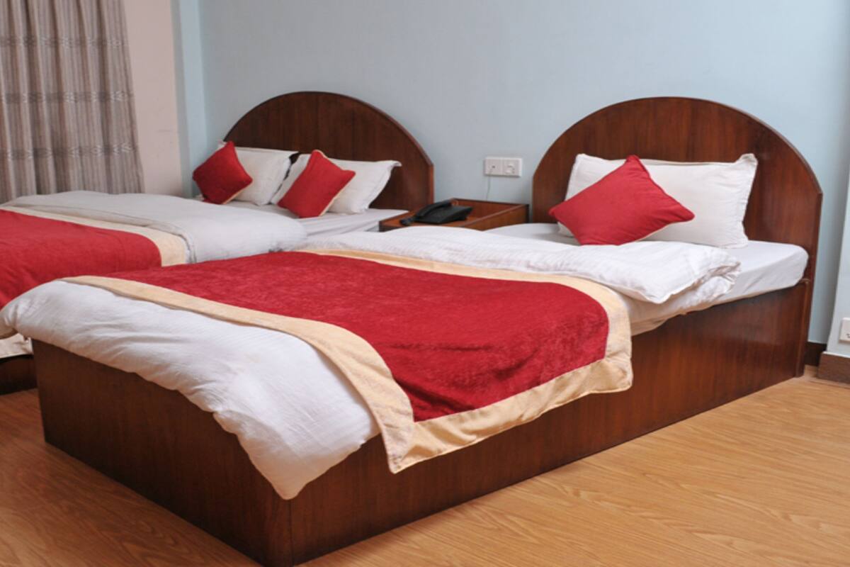 Een tweepersoonsbed met een houten hoofdbord, een rood-witte dekbedovertrek en een rood kussen.