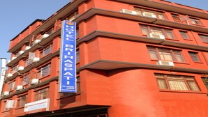 A red building with a sign for Hotel Brihaspati. - MeroStay 035 Hotel Brihaspati (Kathmandu)