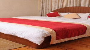 A bed with a red and white bedspread, a wooden headboard, and a beige curtain in the background. - MeroStay 035 Hotel Brihaspati (Kathmandu)