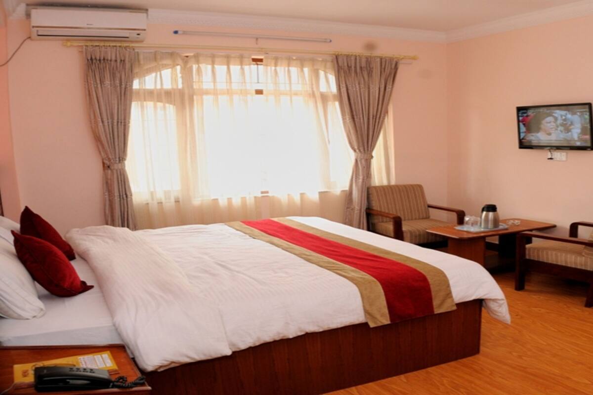 Een hotelkamer met een groot bed, een bureau, een stoel, een televisie en een airconditioning.
