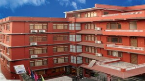 A multi-story hotel with a red facade, multiple balconies, and air conditioning units. - MeroStay 035 Hotel Brihaspati (Kathmandu)