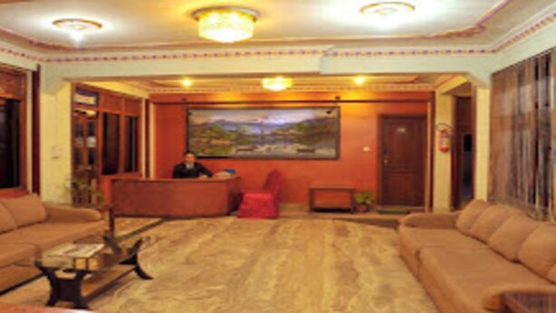 A spacious living room with a large sofa set, a coffee table, and a painting on the wall. - MeroStay 035 Hotel Brihaspati (Kathmandu)