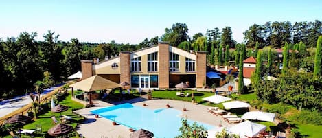 Un resort con piscina, sillones de descanso y un edificio grande con múltiples ventanas.