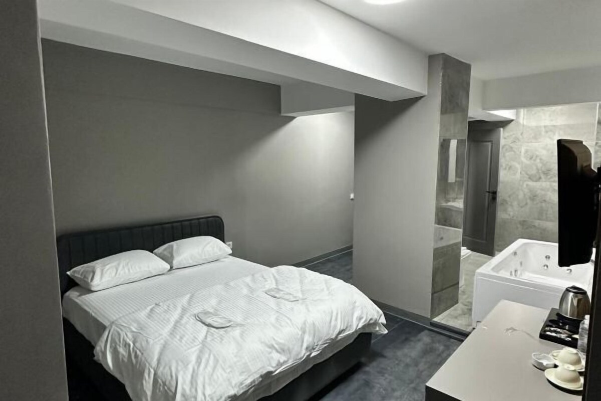 Ein modernes Hotelzimmer mit einem Bett, einem Badezimmer mit Badewanne und einem weißen Schminktisch.
