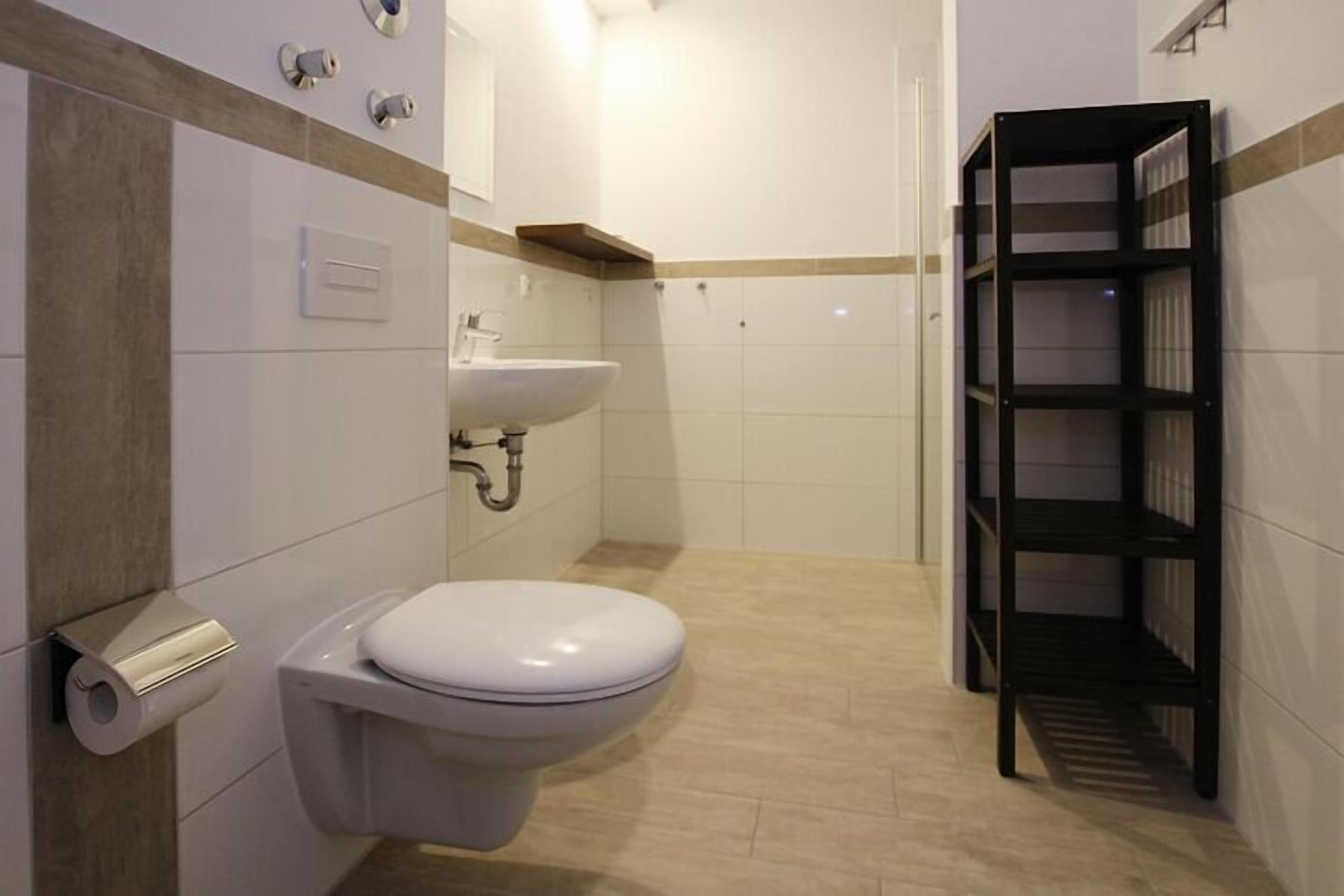 Een badkamer met toilet, wastafel en een plankkast.