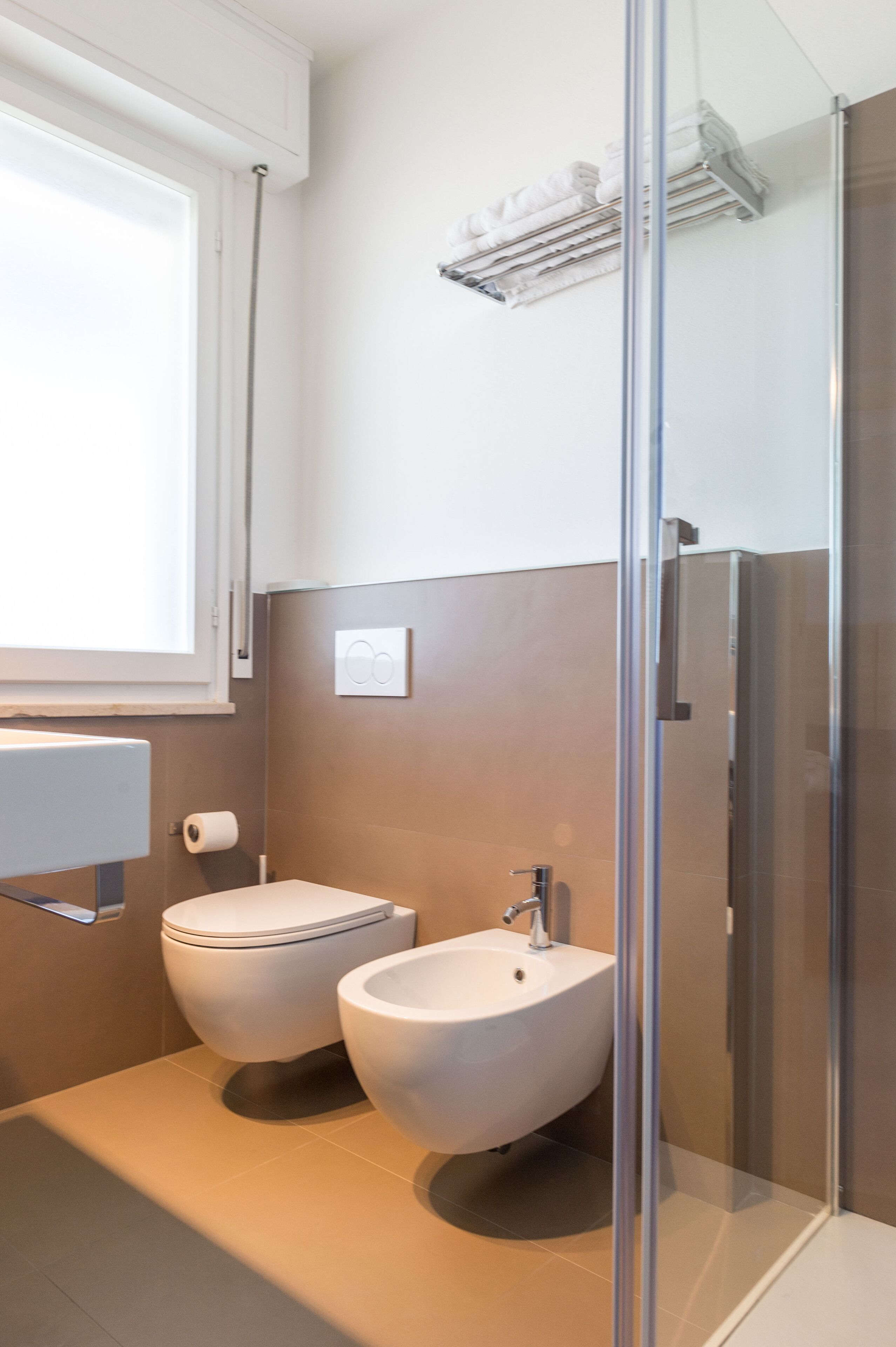 Ein modernes Badezimmer mit Toilette, Bidet und Duschkabine aus Glas.