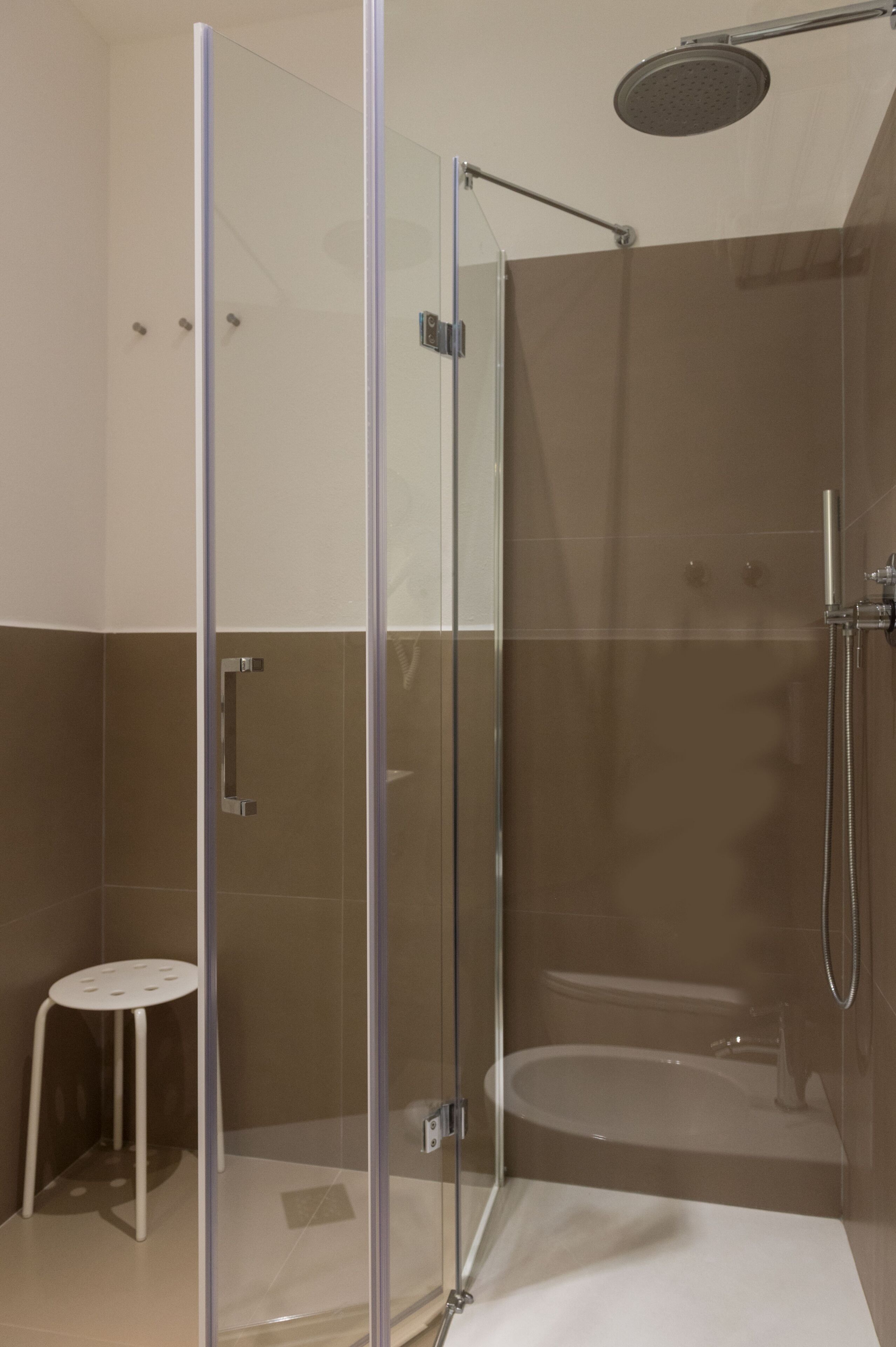A modern bathroom with a glass-enclosed shower, a white pedestal sink, and a bathtub.