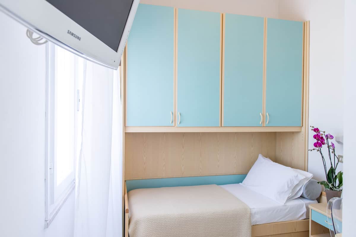 Un dormitorio con cama, televisor y armarios azul claro.