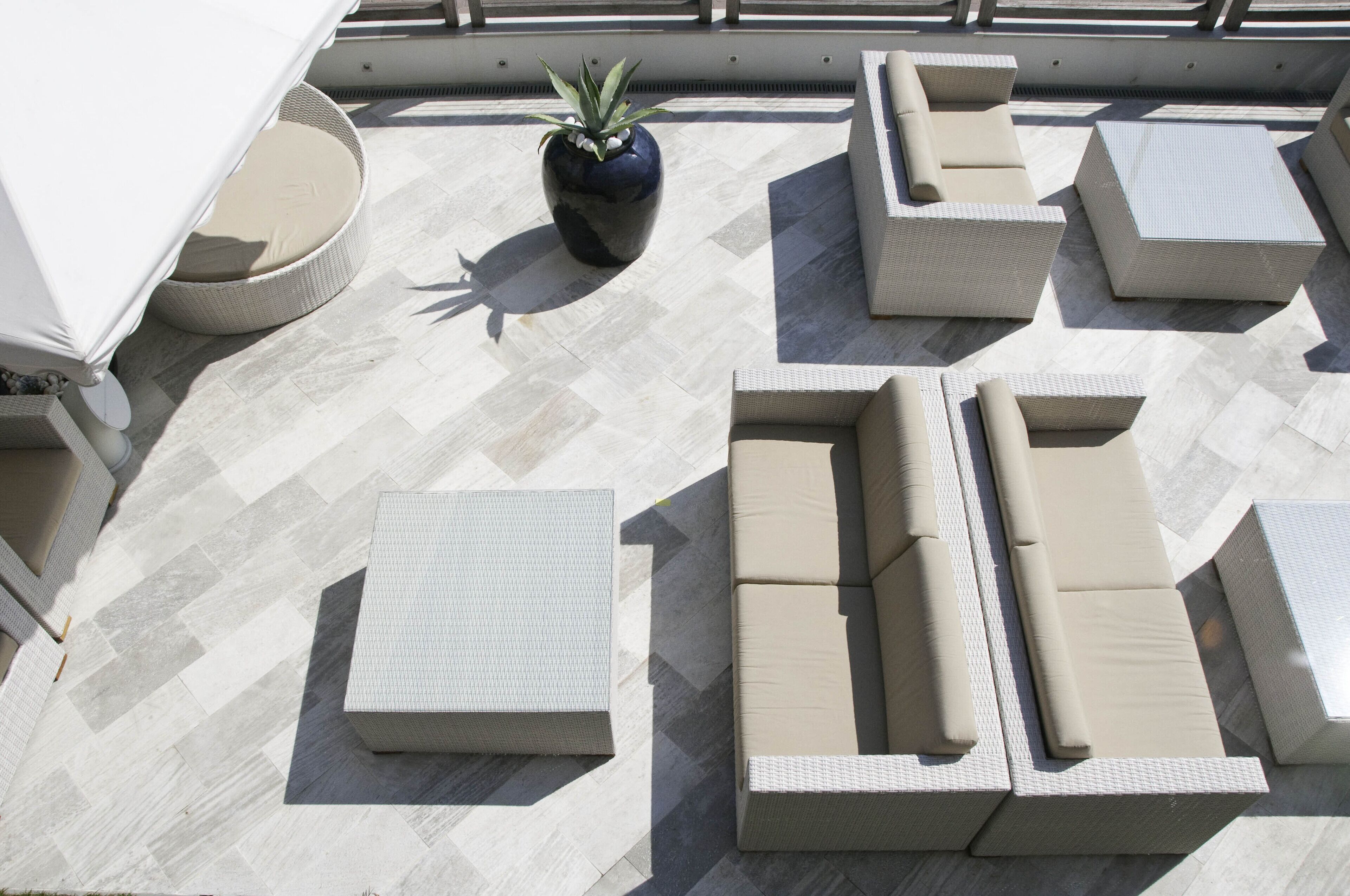 A rooftop terrace with outdoor furniture, including sofas and a table, and a potted plant.