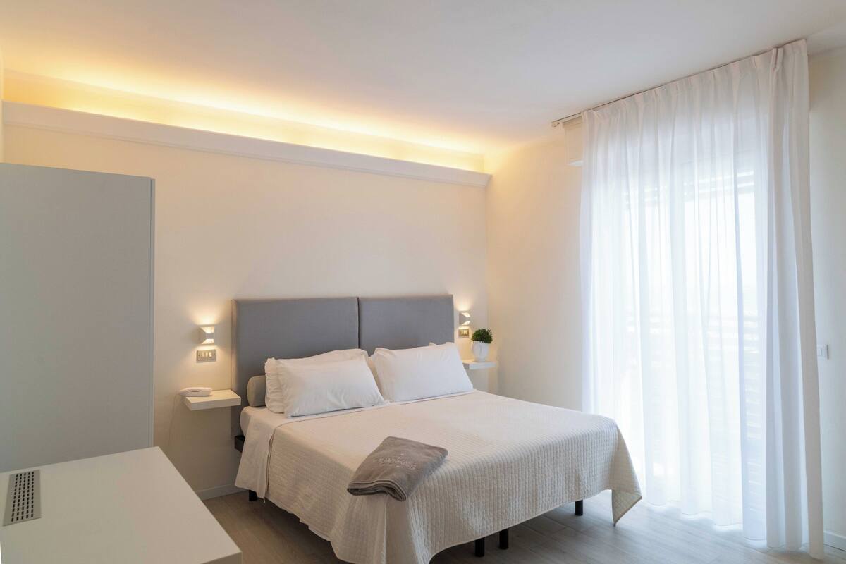 Un dormitorio moderno con cama, mesitas de noche y un velador.