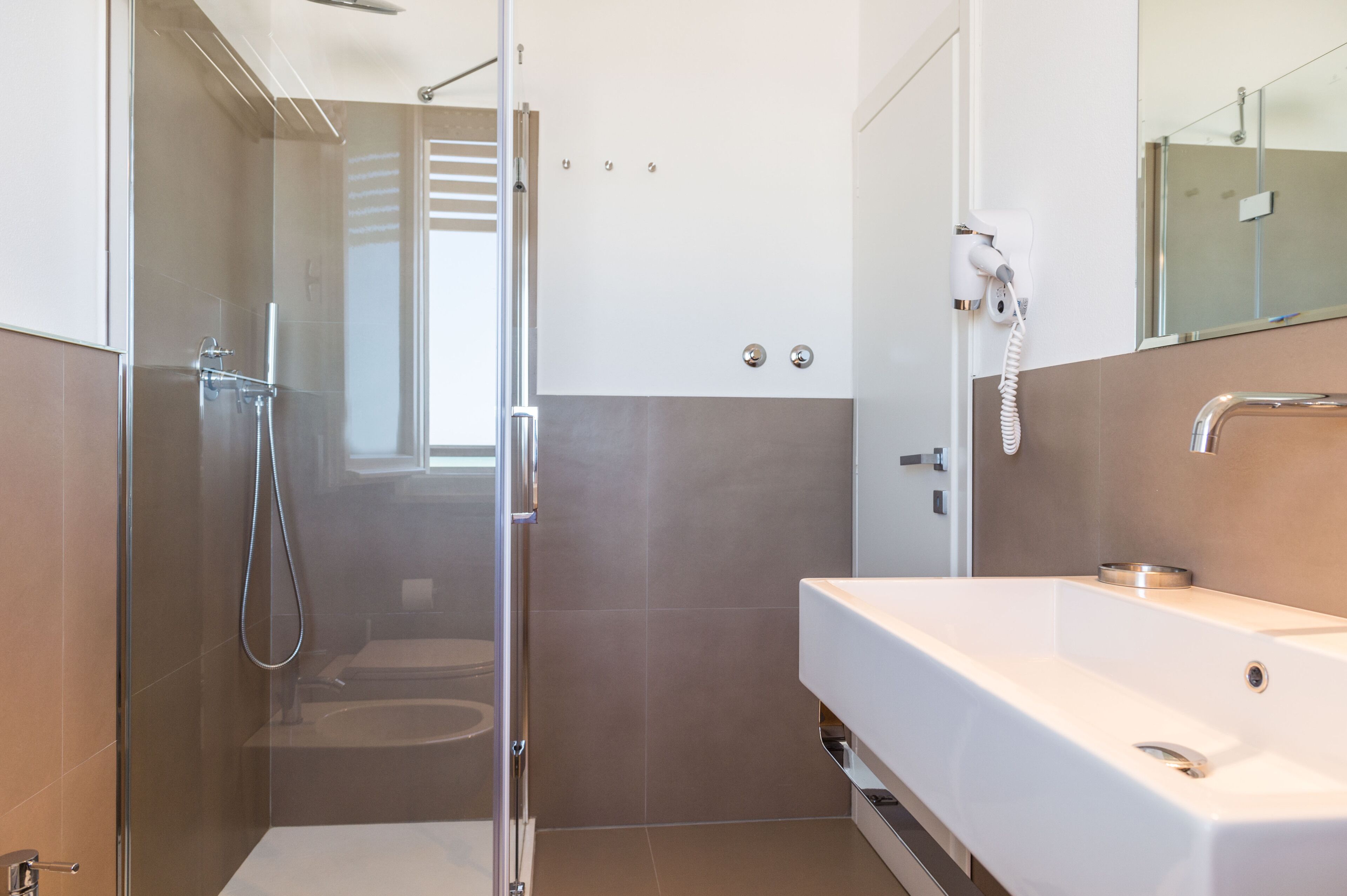 A modern bathroom with a glass-enclosed shower, a white sink, and a mirror.