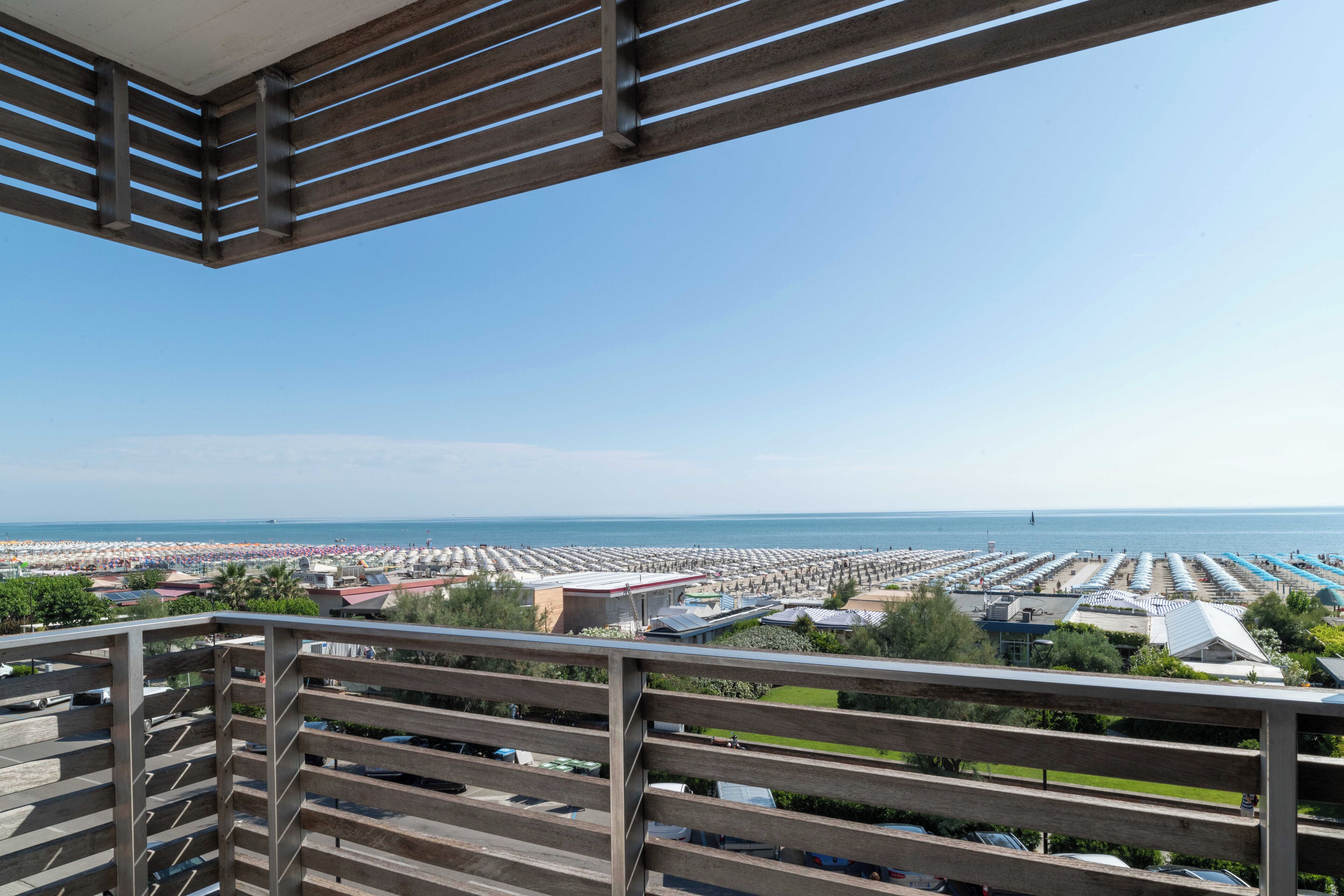 Ein Balkon mit Blick auf einen Strand und ein großer Parkplatz.