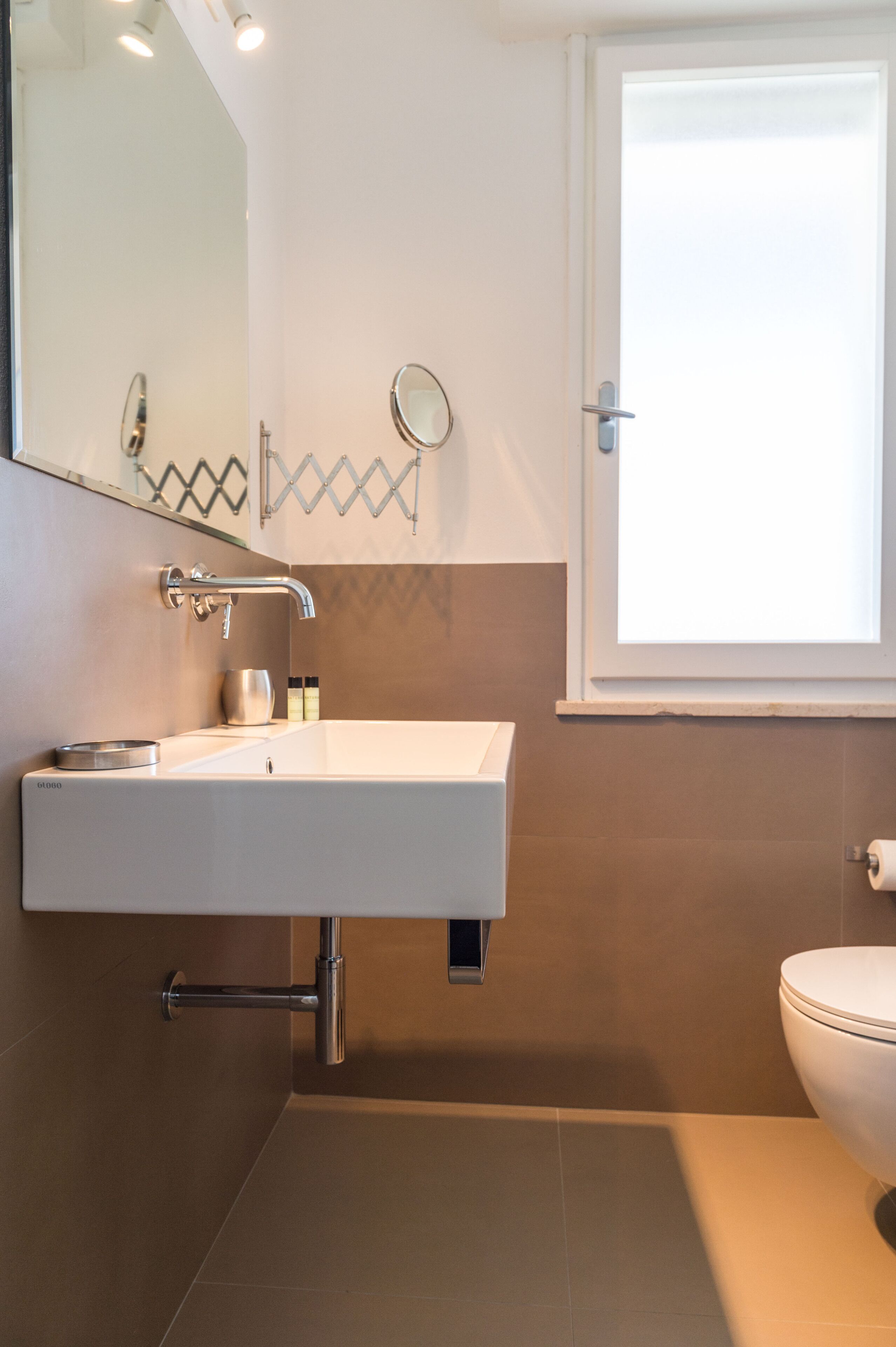Un baño con un lavamanos blanco, un espejo y un inodoro.