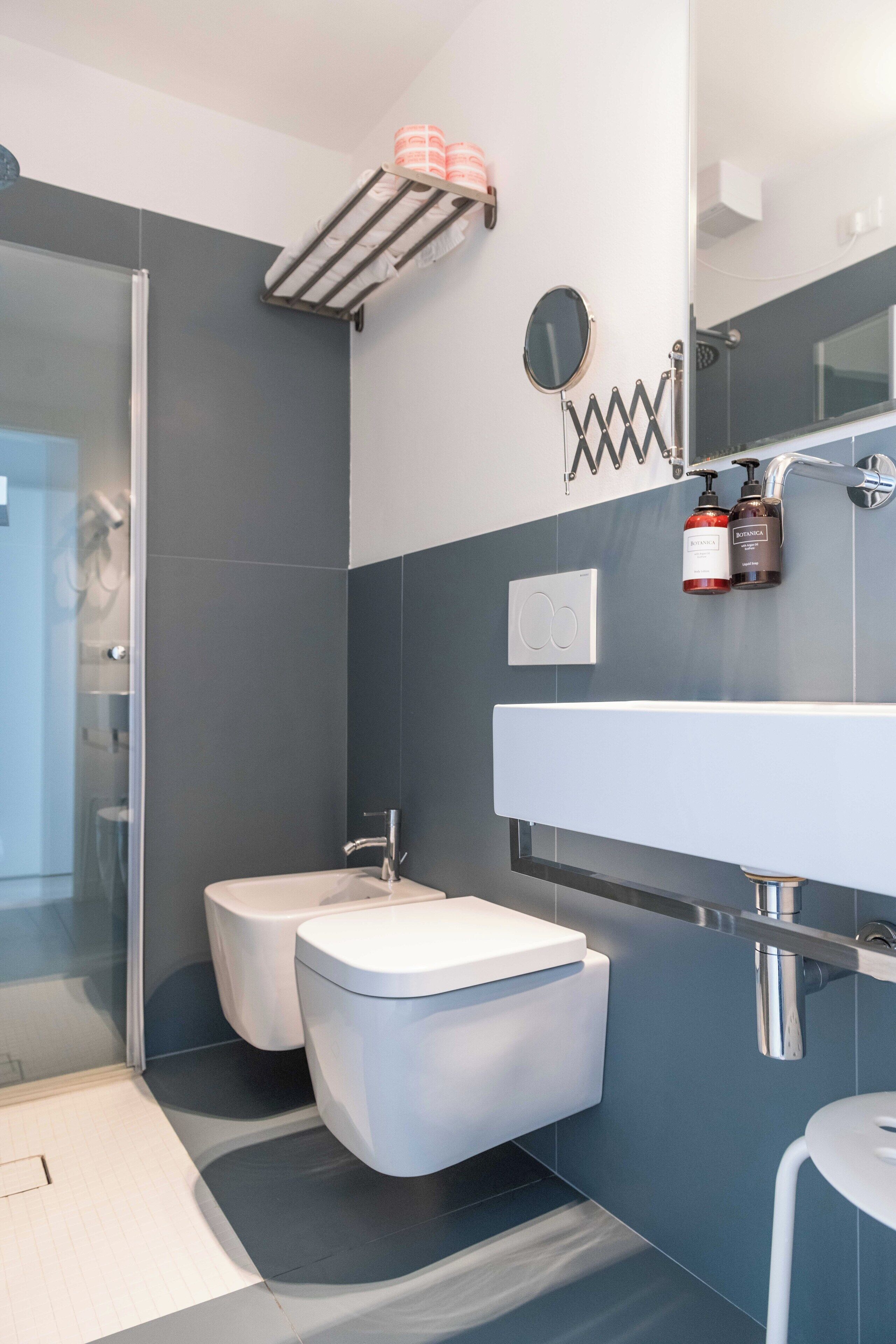 A modern bathroom with a glass shower enclosure, a white sink, and a large mirror.