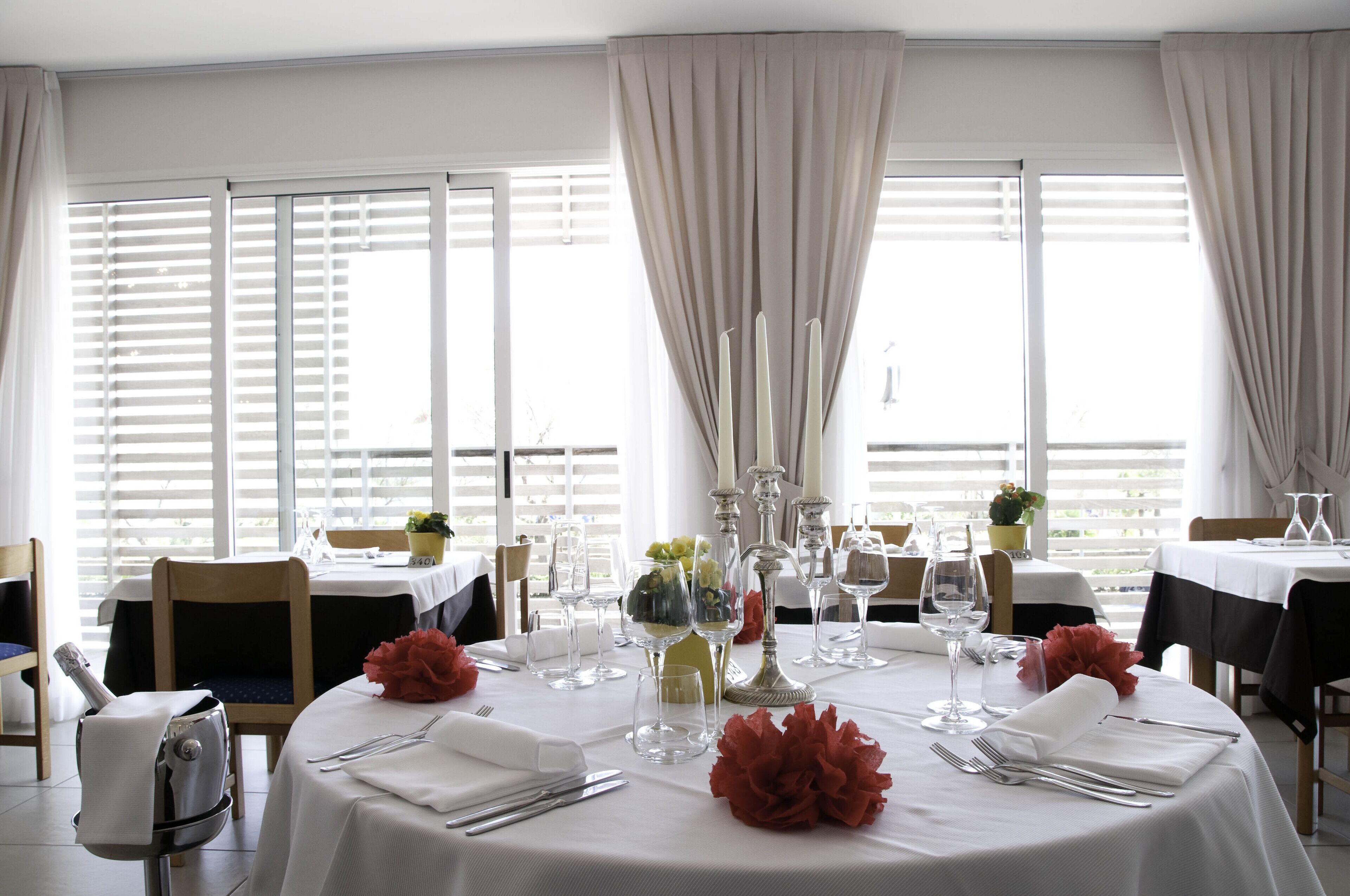 A dining area with tables set for a meal, featuring white tablecloths, silverware, and glassware.